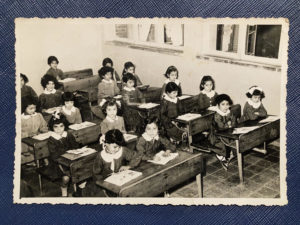 Peacock aged 8, seated in the middle row with white rabbit bunches, at the Firuzkuhi school in 1956; photo courtesy of Jila Peacock.